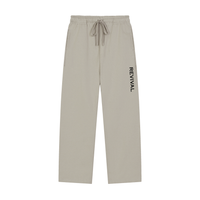 A pair of light beige drawstring sweatpants with the brand name 'REVIVAL' printed vertically in black on the left leg, shown against a plain white background.
