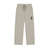A pair of light beige drawstring sweatpants with a small colorful graphic patch on the left hip, displayed against a solid white background.