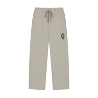A pair of light beige drawstring sweatpants with a small colorful graphic patch on the left hip, displayed against a solid white background.