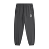 Dark gray tapered jogger pants with a drawstring waist, side pockets, elastic cuffs, and a small white monogram logo on the upper thigh.



