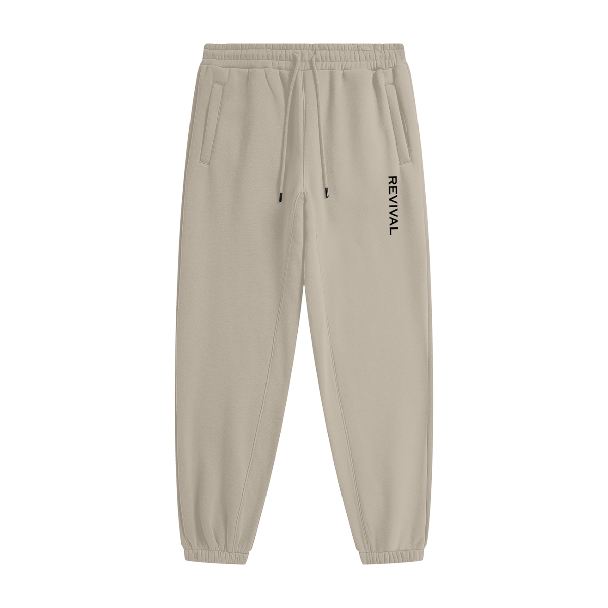 Beige tapered jogger pants with an elastic drawstring waistband, side pockets, elastic cuffs, and vertical black REVIVAL lettering on the upper thigh.

