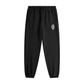 Black tapered jogger pants with a drawstring waist, side pockets, elastic cuffs, and a small white monogram logo on the upper thigh.