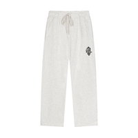 Light heather gray sweatpants with an elastic drawstring waist and a small green circular patch on the left thigh, shown against a plain white background.